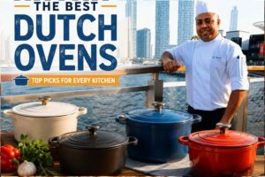Smiling chef standing on a waterfront promenade beside colorful Dutch ovens, with a modern city skyline in the background and the text "The Best Dutch Ovens – Top Picks for Every Kitchen."