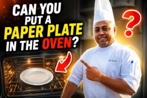 A professional chef in a white uniform and tall chef hat stands beside an open oven, smiling and pointing at a white paper plate. Large bold text reads, “CAN YOU PUT A PAPER PLATE IN THE OVEN?” The oven glows with warm light, while a neon question mark, flame icon, and checklist reading “Safe? Burn? Melt?” create a dramatic, attention-grabbing feature image about oven safety and paper plates.