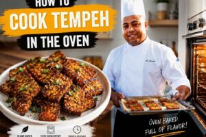 Feature image showing a chef in a white uniform holding a tray of oven-baked tempeh in a modern kitchen beside a plate of crispy roasted tempeh. Bold text reads "How to Cook Tempeh in the Oven," highlighting an easy plant-based recipe with crispy, delicious results.
