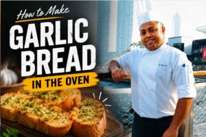 A professional chef in a white uniform stands on a waterfront promenade with a modern city skyline in the background. Beside him is a close-up image of golden, toasted garlic bread garnished with herbs. Large headline text reads, “How to Make Garlic Bread in the Oven,” with additional text highlighting the recipe as easy, buttery, crispy, and delicious.