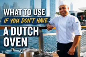 A professional chef in a white uniform and tall chef’s hat stands on a waterfront boardwalk with a modern city skyline in the background. Large bold text reads, “What to Use If You Don’t Have a Dutch Oven.” In the foreground, a wooden table displays three cookware alternatives: a cast-iron pot, a stainless-steel stockpot, and a covered skillet, illustrating substitutes for a Dutch oven. The bright, high-contrast design creates an engaging feature image for a cooking article.